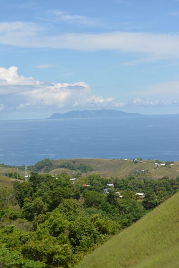 Discover the serene beauty of the lush green landscapes meeting the azure sea in the Solomon Islands.
