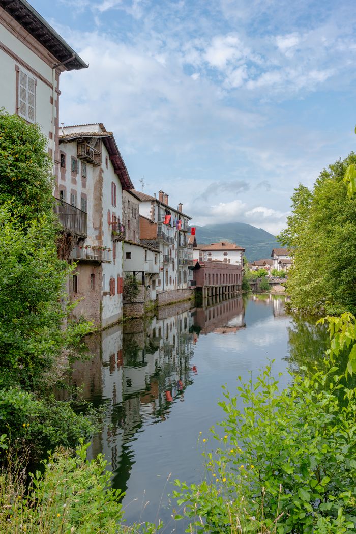 Scenic view of traditional buildings by the river in Elizondo, Spain on a sunny day.