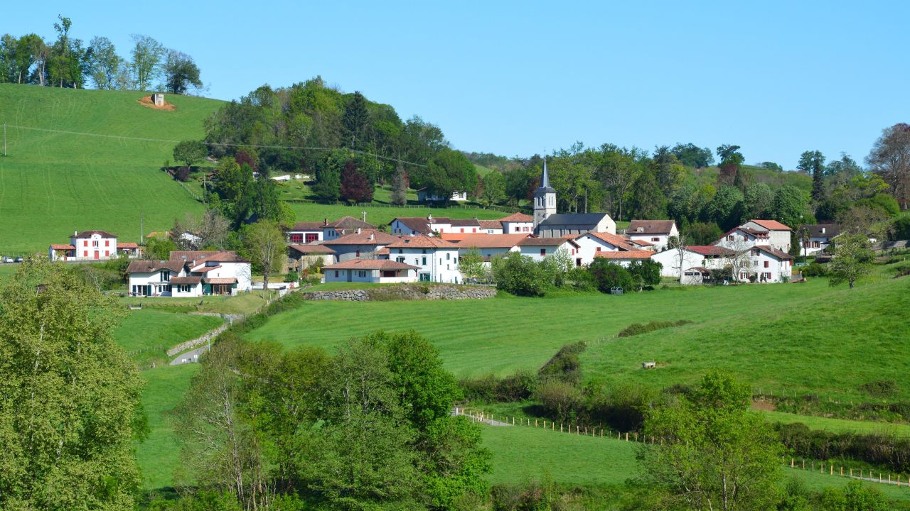 Idyllic rural village of Lacarre in Nouvelle-Aquitaine, France, surrounded by lush green fields and hills.